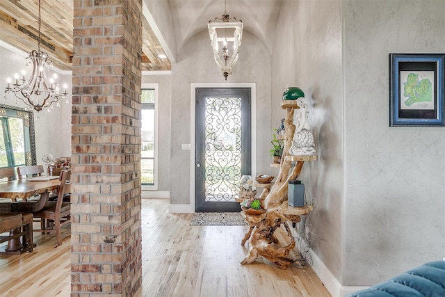 entrance foyer featuring high vaulted ceiling, a notable chandelier, and light hardwood / wood-style floors