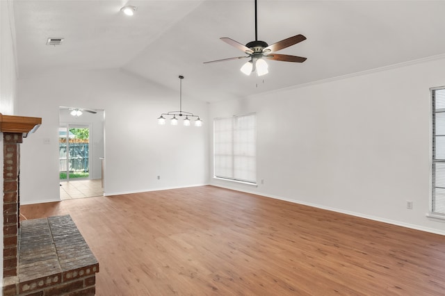 unfurnished living room featuring hardwood / wood-style floors, a brick fireplace, ceiling fan, lofted ceiling, and crown molding