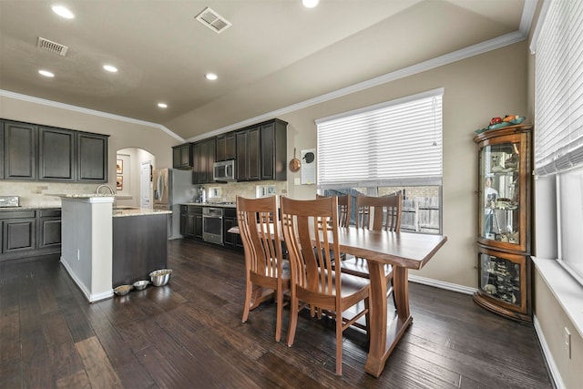 dining space featuring dark wood-type flooring, crown molding, lofted ceiling, and sink