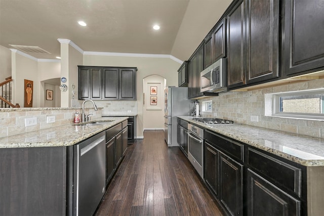 kitchen featuring kitchen peninsula, appliances with stainless steel finishes, dark hardwood / wood-style floors, ornamental molding, and sink