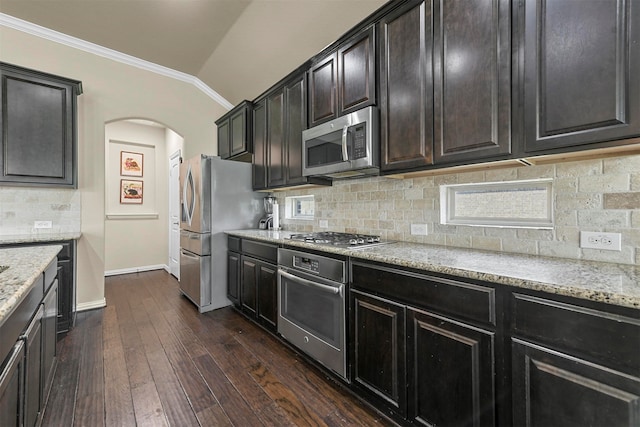 kitchen with vaulted ceiling, appliances with stainless steel finishes, decorative backsplash, and dark hardwood / wood-style floors