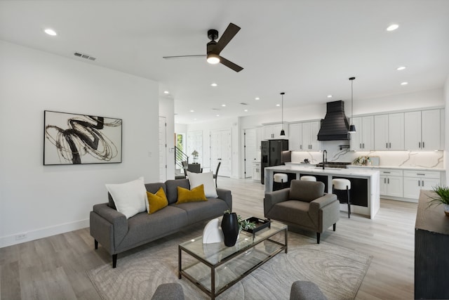 living room with sink, light hardwood / wood-style flooring, and ceiling fan