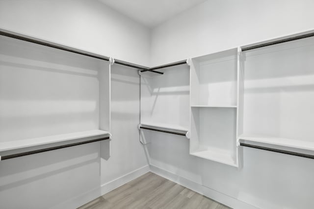 walk in closet with light hardwood / wood-style flooring