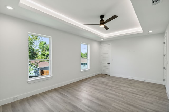 unfurnished room with ceiling fan, a raised ceiling, and light hardwood / wood-style floors