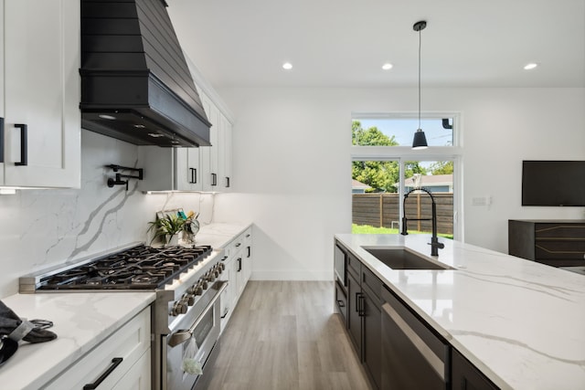 kitchen with white cabinets, premium range hood, sink, hanging light fixtures, and appliances with stainless steel finishes