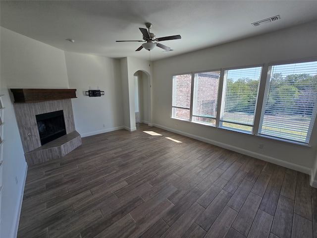 unfurnished living room with ceiling fan, dark wood-type flooring, and a tile fireplace