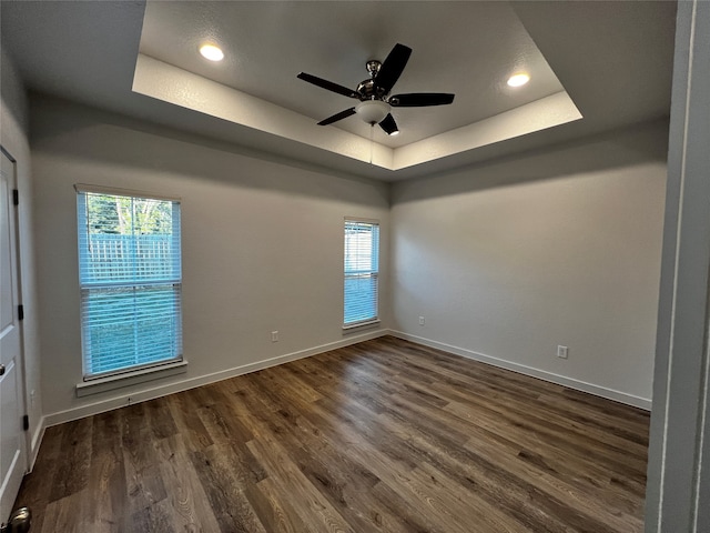 unfurnished room with a tray ceiling, dark hardwood / wood-style flooring, and ceiling fan