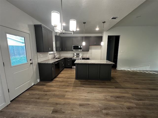 kitchen featuring dark hardwood / wood-style floors, light stone countertops, decorative light fixtures, and stainless steel appliances