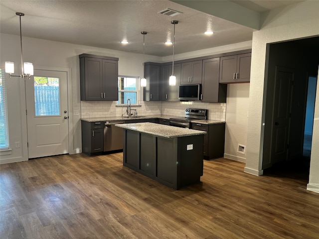 kitchen featuring stainless steel appliances, dark wood-type flooring, a kitchen island, and a wealth of natural light