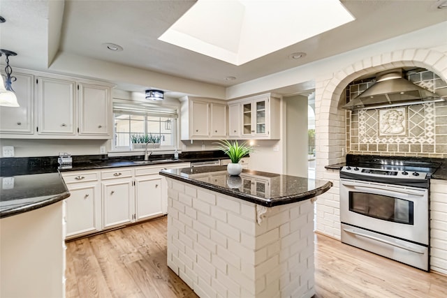 kitchen featuring stainless steel range oven, a center island, wall chimney exhaust hood, pendant lighting, and white cabinets