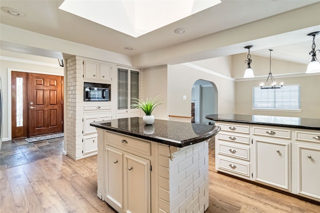 kitchen featuring light hardwood / wood-style floors, lofted ceiling, white cabinets, and a center island