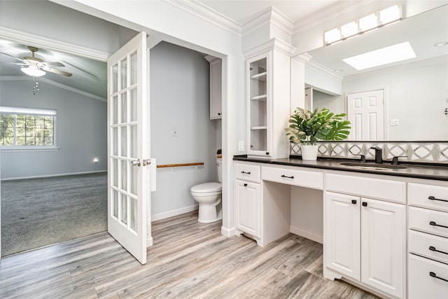 bathroom with toilet, crown molding, vaulted ceiling with skylight, and vanity