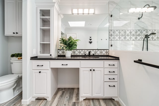 bathroom featuring hardwood / wood-style flooring, toilet, ornamental molding, vanity, and walk in shower