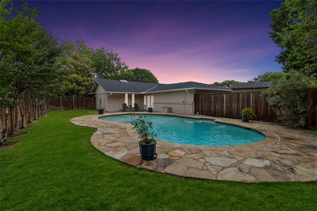 pool at dusk with a patio area and a yard