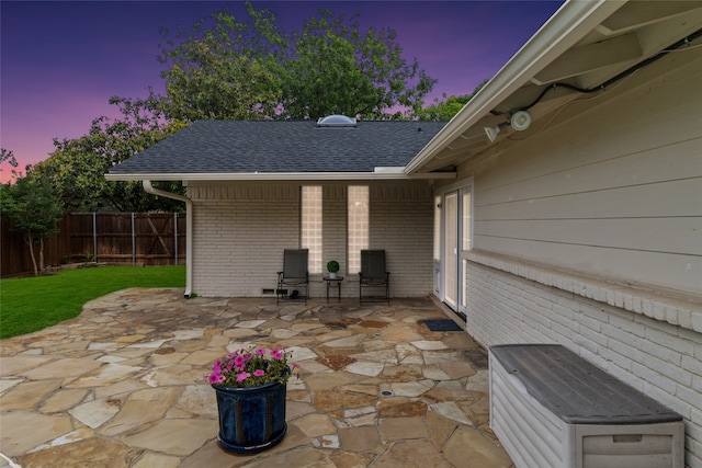 patio terrace at dusk featuring a lawn