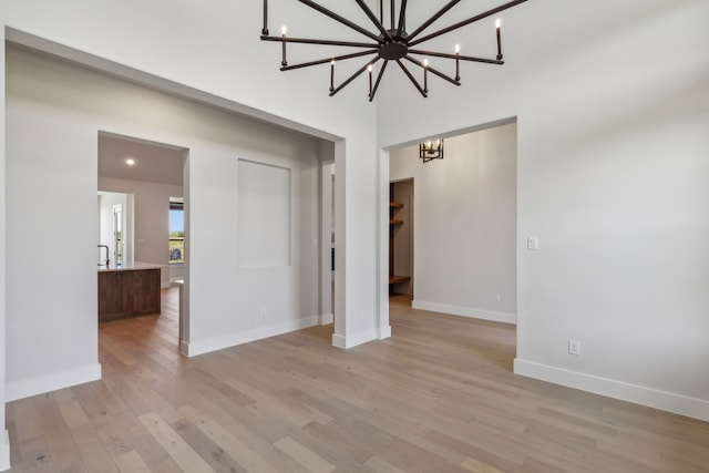 unfurnished room with an inviting chandelier and light hardwood / wood-style flooring