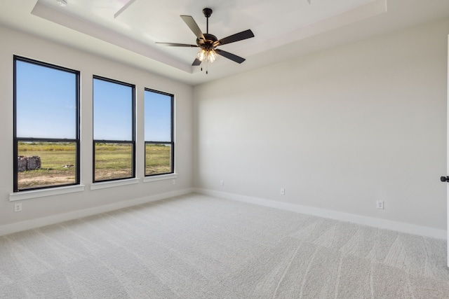 carpeted spare room with ceiling fan and a tray ceiling