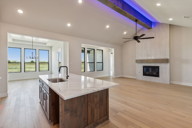 kitchen featuring a center island with sink, light hardwood / wood-style flooring, lofted ceiling with beams, and plenty of natural light