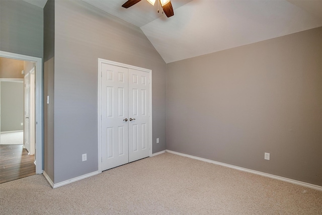 unfurnished bedroom featuring ceiling fan, a closet, vaulted ceiling, and carpet