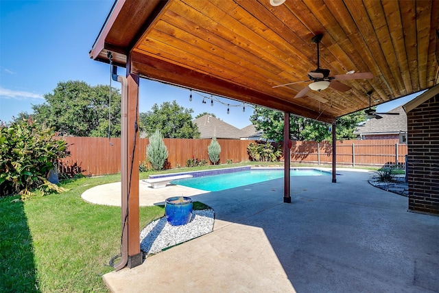 view of swimming pool with ceiling fan, a patio, a diving board, and a lawn