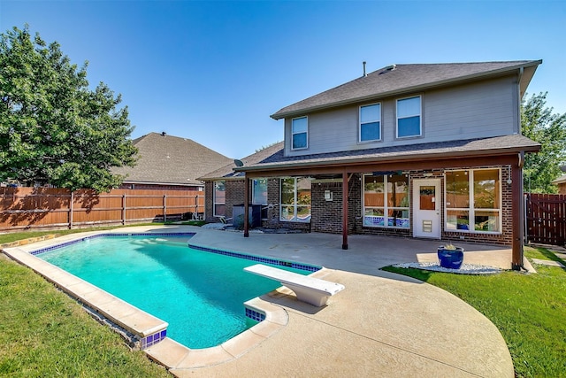 view of swimming pool featuring a yard, a patio, and a diving board