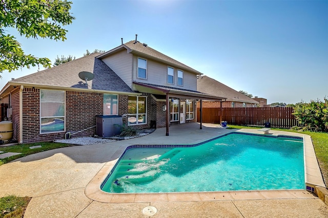 back of property with a fenced in pool and a patio area