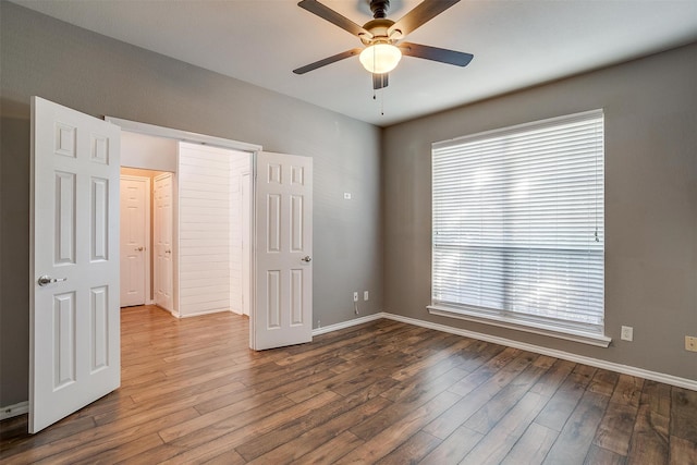 unfurnished bedroom with hardwood / wood-style floors, multiple windows, and ceiling fan