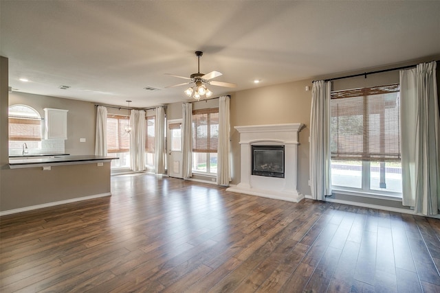 unfurnished living room featuring ceiling fan, dark hardwood / wood-style floors, and sink