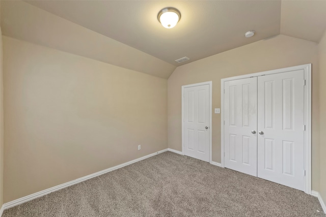 unfurnished bedroom featuring carpet floors, vaulted ceiling, and a closet