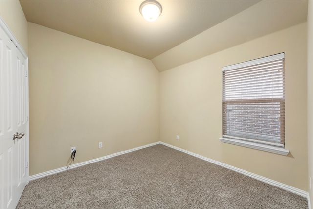 carpeted spare room with lofted ceiling