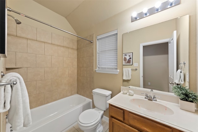 full bathroom featuring tile patterned flooring, toilet, lofted ceiling, tiled shower / bath, and vanity