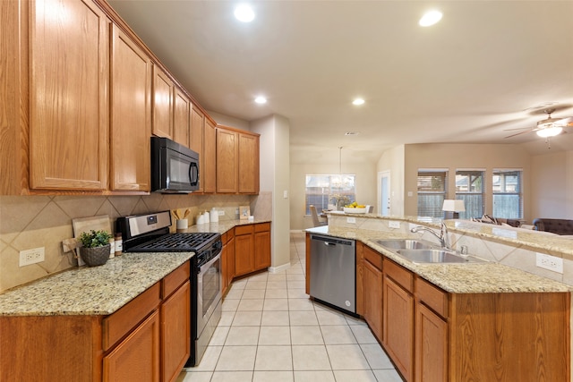 kitchen featuring decorative backsplash, sink, ceiling fan with notable chandelier, pendant lighting, and appliances with stainless steel finishes