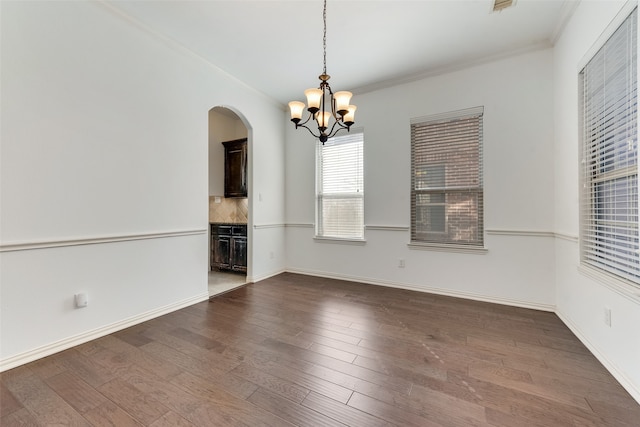 unfurnished room with ornamental molding, a notable chandelier, and dark wood-type flooring