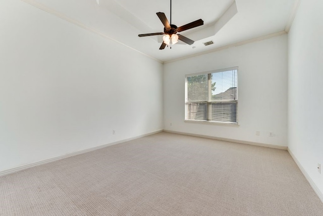 carpeted spare room with crown molding, ceiling fan, and a raised ceiling