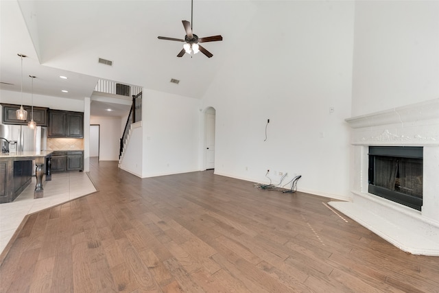 unfurnished living room with high vaulted ceiling, ceiling fan, and hardwood / wood-style floors