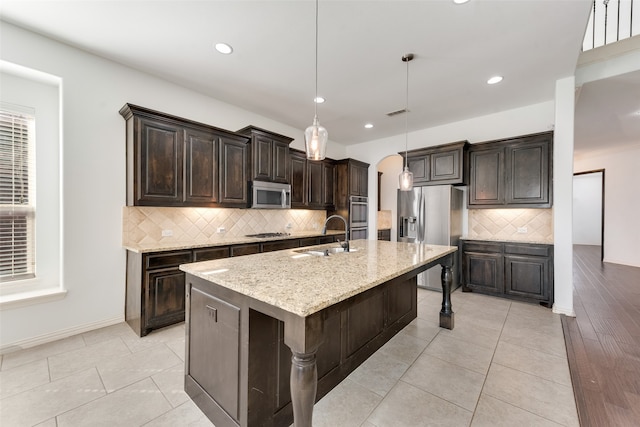 kitchen with light hardwood / wood-style flooring, decorative light fixtures, a center island with sink, sink, and stainless steel appliances