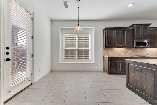 kitchen featuring dark brown cabinets, hanging light fixtures, light tile patterned floors, and a healthy amount of sunlight