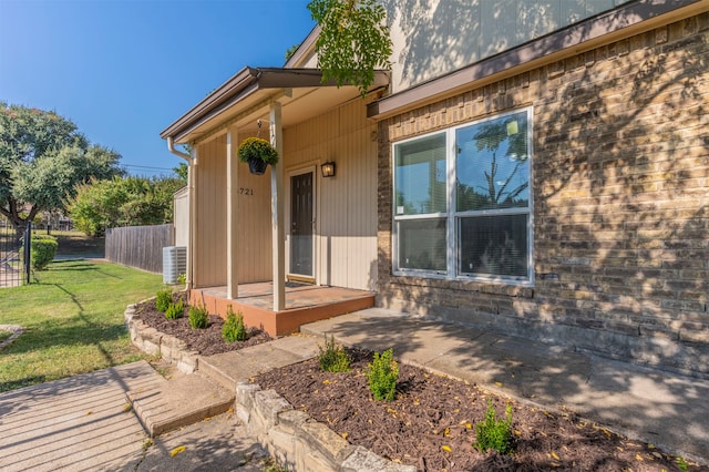 view of exterior entry with cooling unit and a lawn