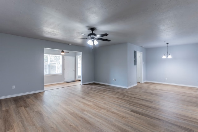 spare room with ceiling fan with notable chandelier, light hardwood / wood-style floors, and a textured ceiling