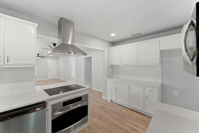 kitchen featuring white cabinetry, stainless steel appliances, light wood-style floors, island range hood, and light countertops