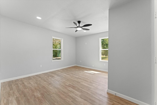 spare room with light wood finished floors, plenty of natural light, a ceiling fan, and baseboards