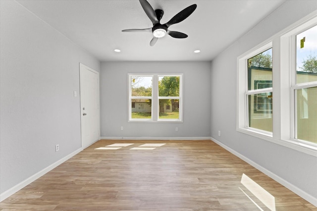 spare room featuring a wealth of natural light, baseboards, and light wood finished floors