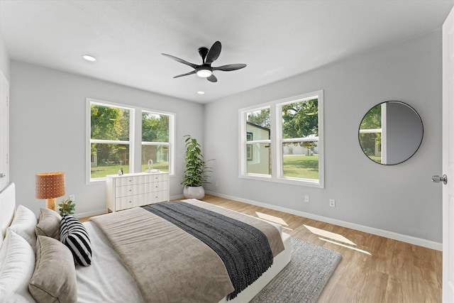 bedroom with recessed lighting, multiple windows, baseboards, and wood finished floors