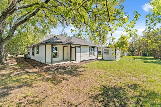 rear view of house with an outdoor structure, central AC unit, a lawn, and a shed