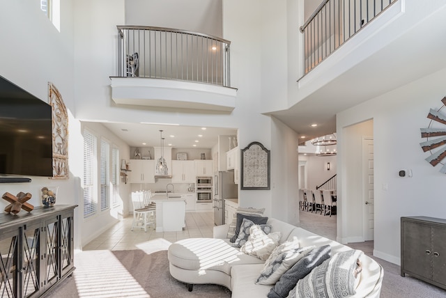 living room with light carpet, a towering ceiling, sink, and a chandelier