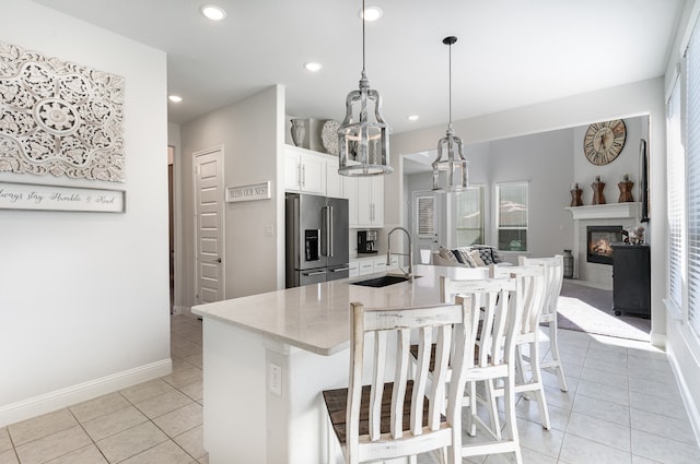 kitchen with white cabinets, sink, a breakfast bar area, decorative light fixtures, and stainless steel refrigerator with ice dispenser