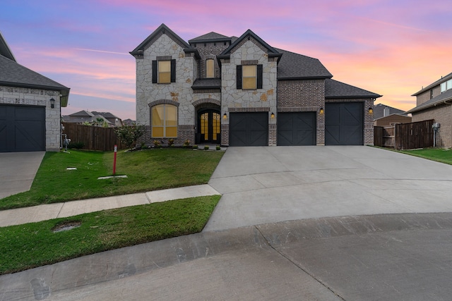 french country inspired facade with a yard and a garage