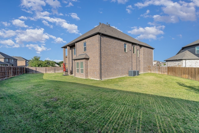 rear view of house featuring central AC and a lawn