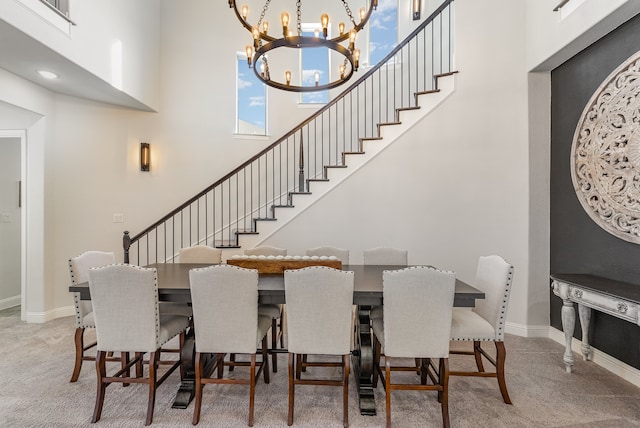 carpeted dining space featuring a towering ceiling and a chandelier