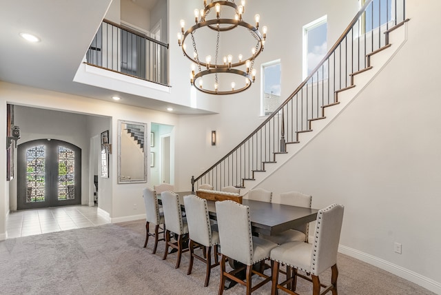 dining room with french doors, light colored carpet, a notable chandelier, and a high ceiling